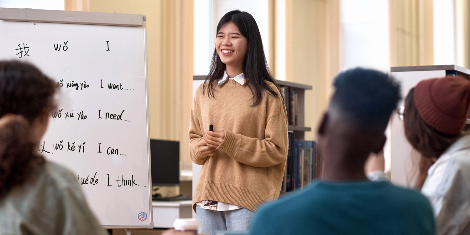 Eine Chinesischlehrerin erklärt ihren Schülern die Konjugation von Verben.