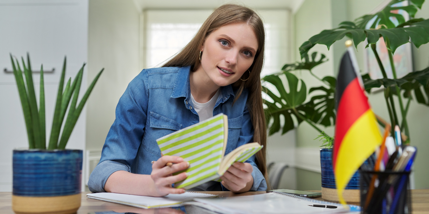 Junge Frau sitzt am Pult und lernt Deutsch als Fremdsprache.