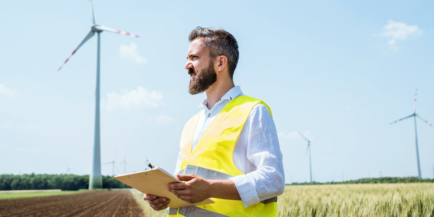 Arbeit im Energiebereich, Mann auf dem offenen Feld vor einem Windrad