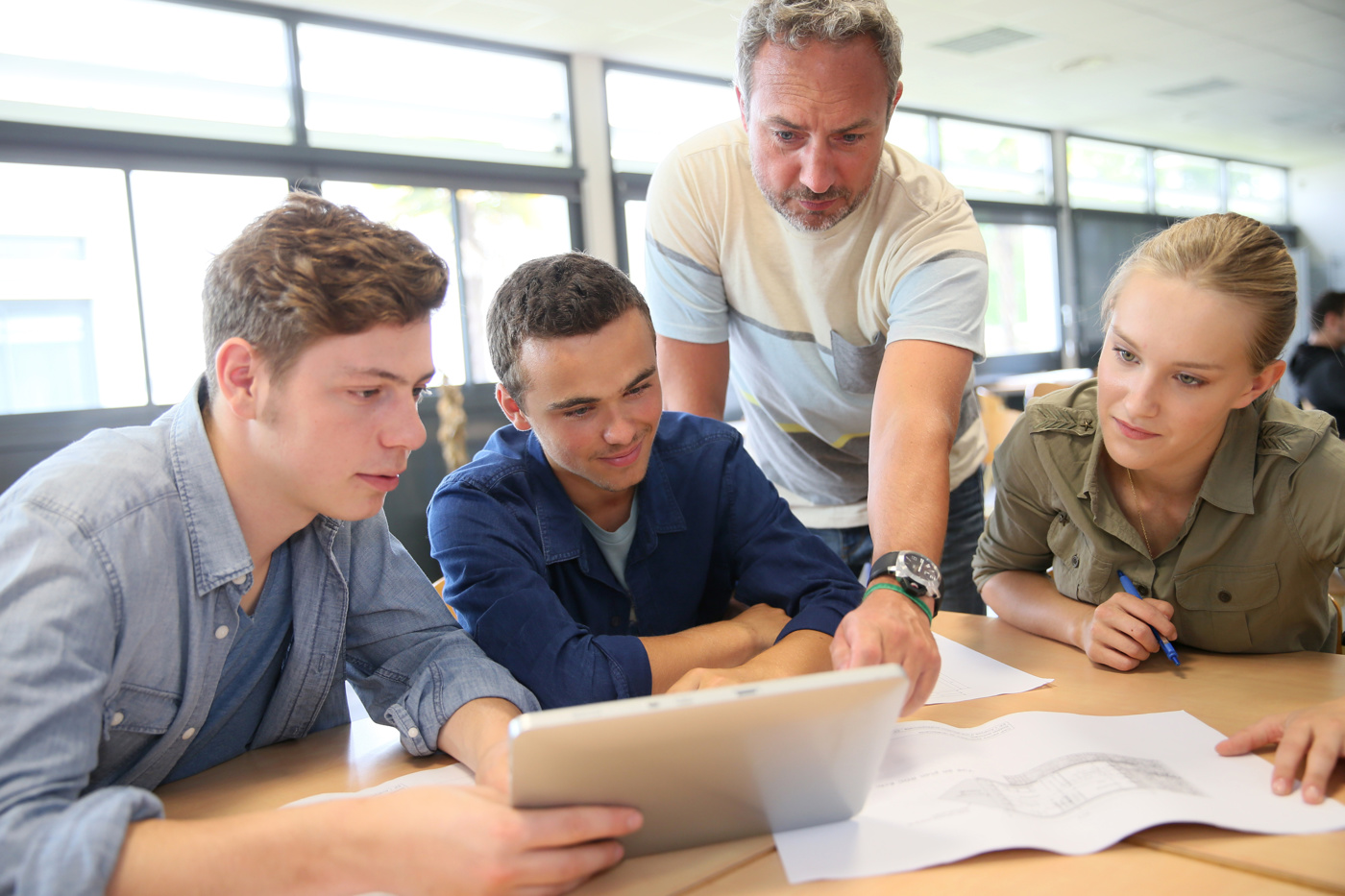 Schüler und Schülerin einer Berufsmaturität-Schule hören gespannt den Worten des Lehrers zu.