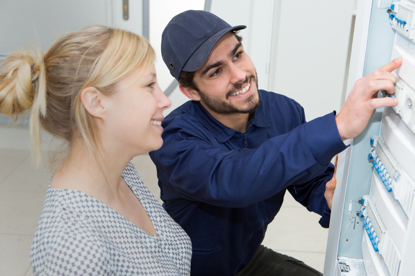 Ein Elektroinstallations- und Sicherheitsexperte erklärt seiner Auftraggeberin die einzelnen Funktionen des Elektro-Kastens.