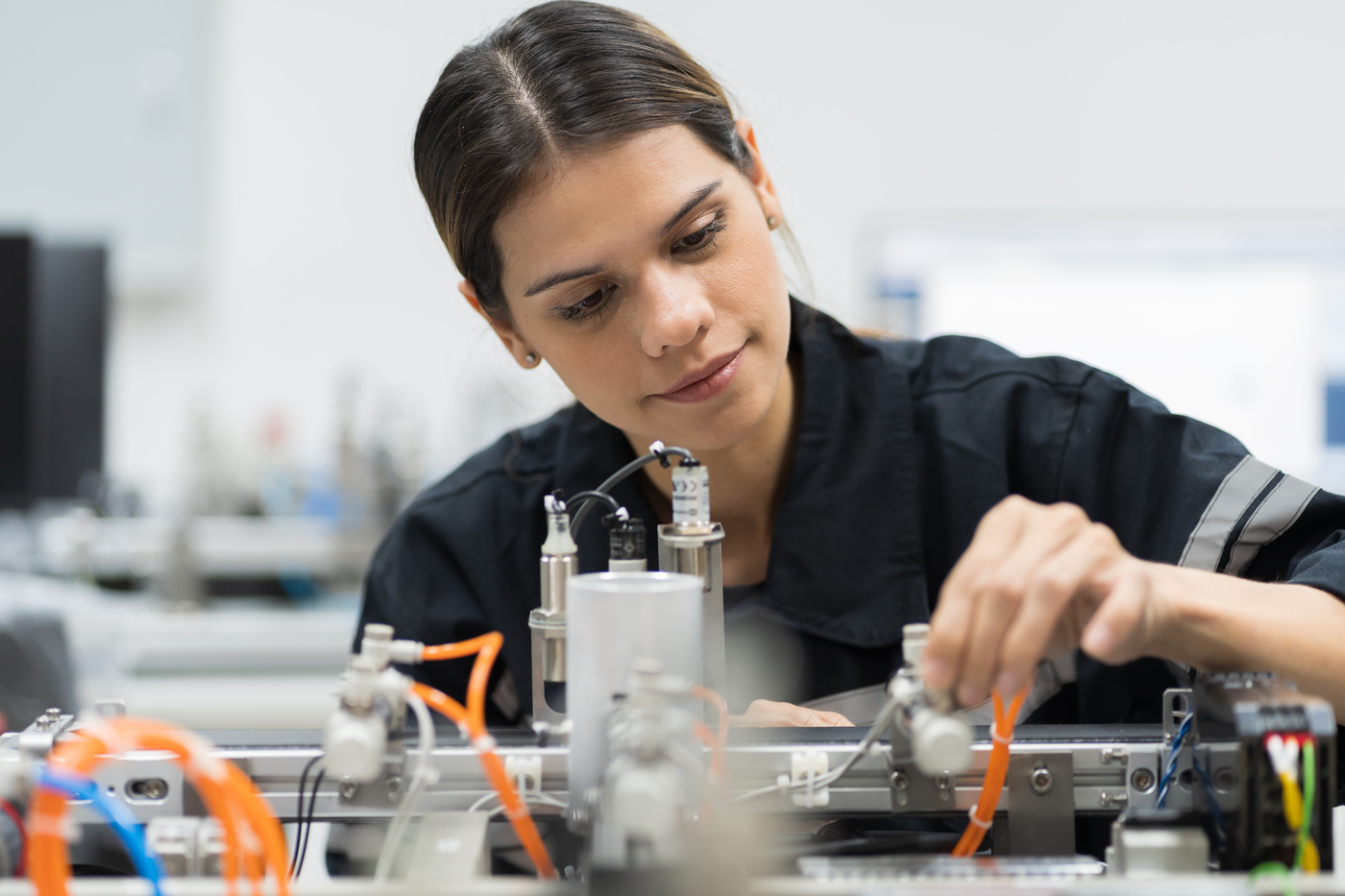 Eine Elektrotechnikerin HF baut ein Gerät zusammen und verkabelt die einzelnen elektrischen Teile miteinander.