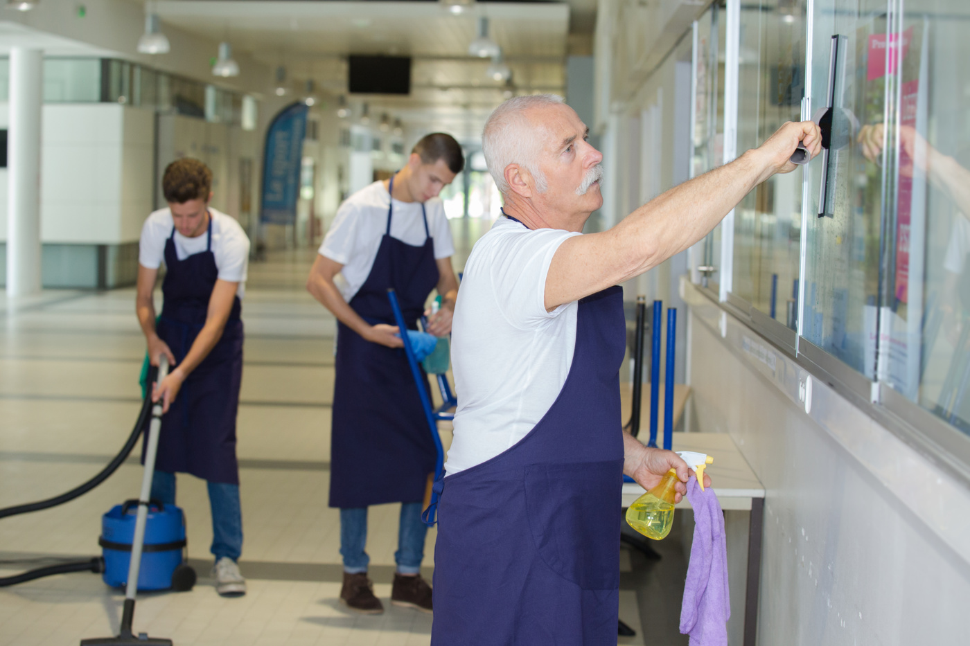 Ein Hausmeister hilft seinem Team bei der Reinigung der Fenster.