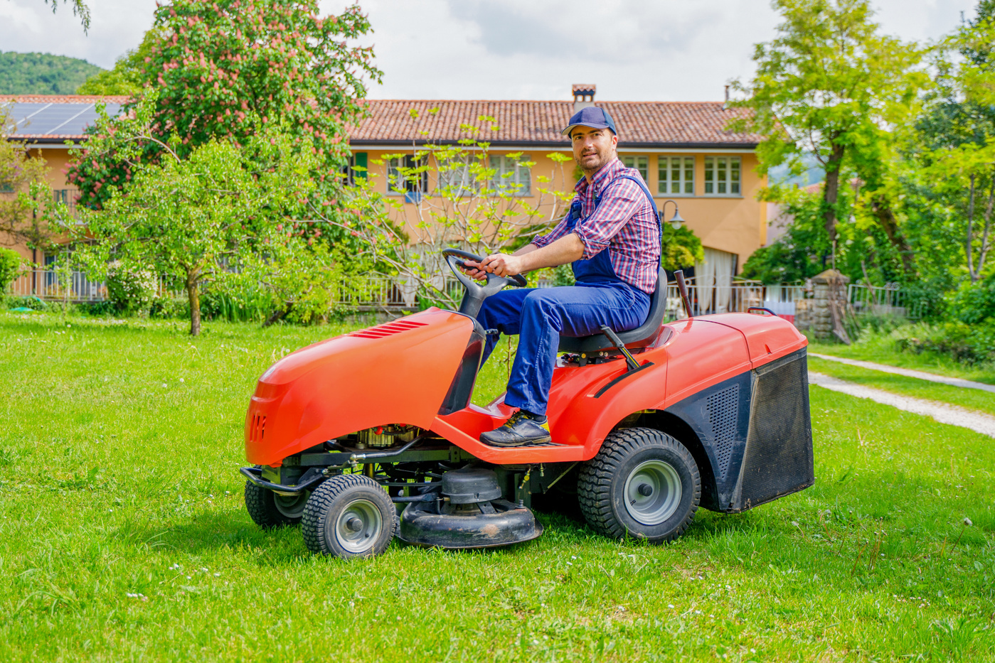 Hauswart mit eidg. Fachausweis mäht den Rasen.