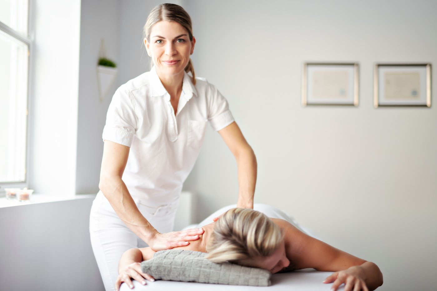 Eine Medizinische Masseurin mit eidg. Fachausweis massiert die verspannten Stellen einer Patientin, um so die Schmerzen zu lindern.