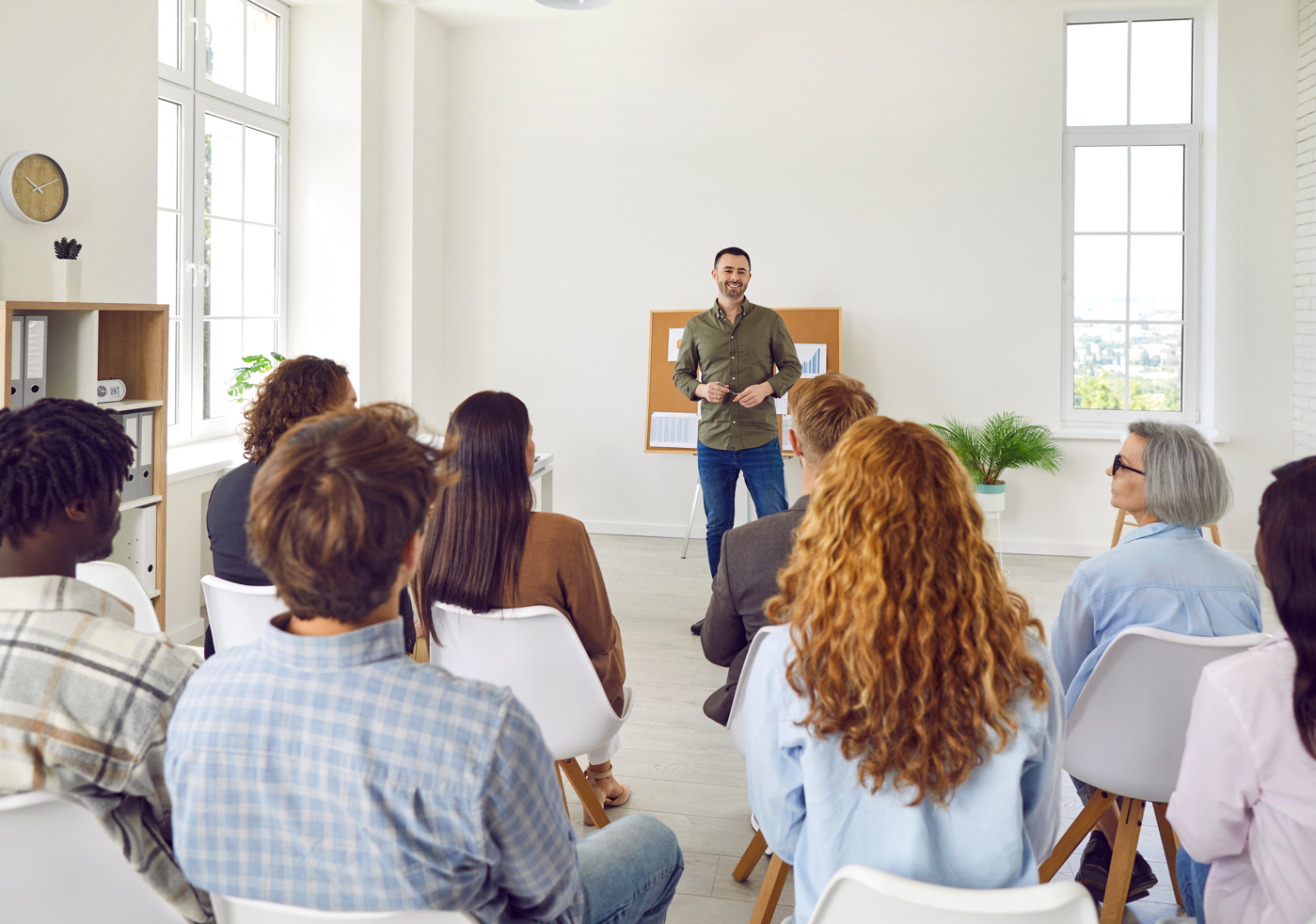 Eine Gruppe Frauen und Männer hört gespannt den Worten eines Business Coaches.
