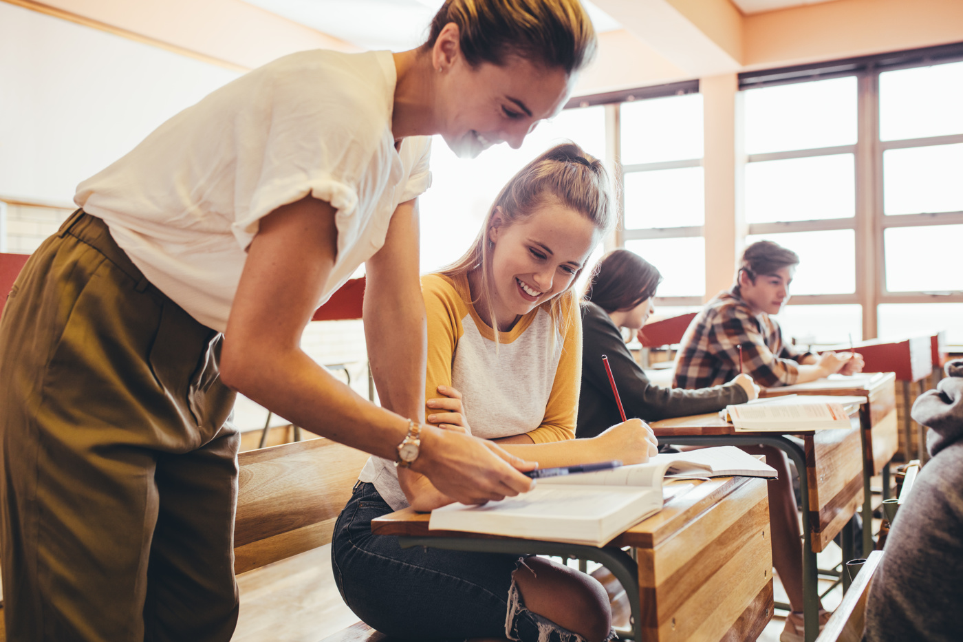 Eine Lehrerin hilft einer Schülerin im Klassenzimmer