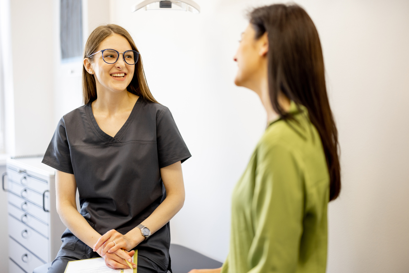 Eine Praxisassistentin befragt die Patientin zu ihrem Wohlbefinden und bringt persönliche Daten, wie ihren Versicherungsanbieter in Erfahrung.