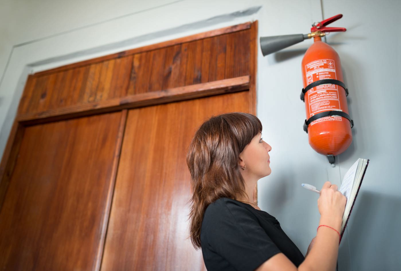 Sicherheitsbeauftragte kontrolliert den Feuerlöscher im Büro.
