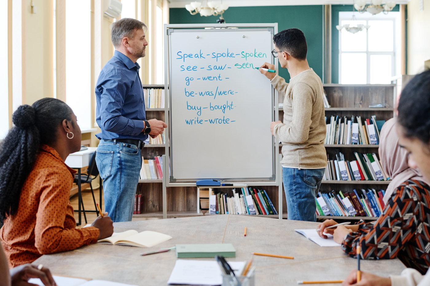 Schüler und Schülerinnen eines Englisch Sprachkurs konjugieren Verben in verschiedenen Zeitformen.