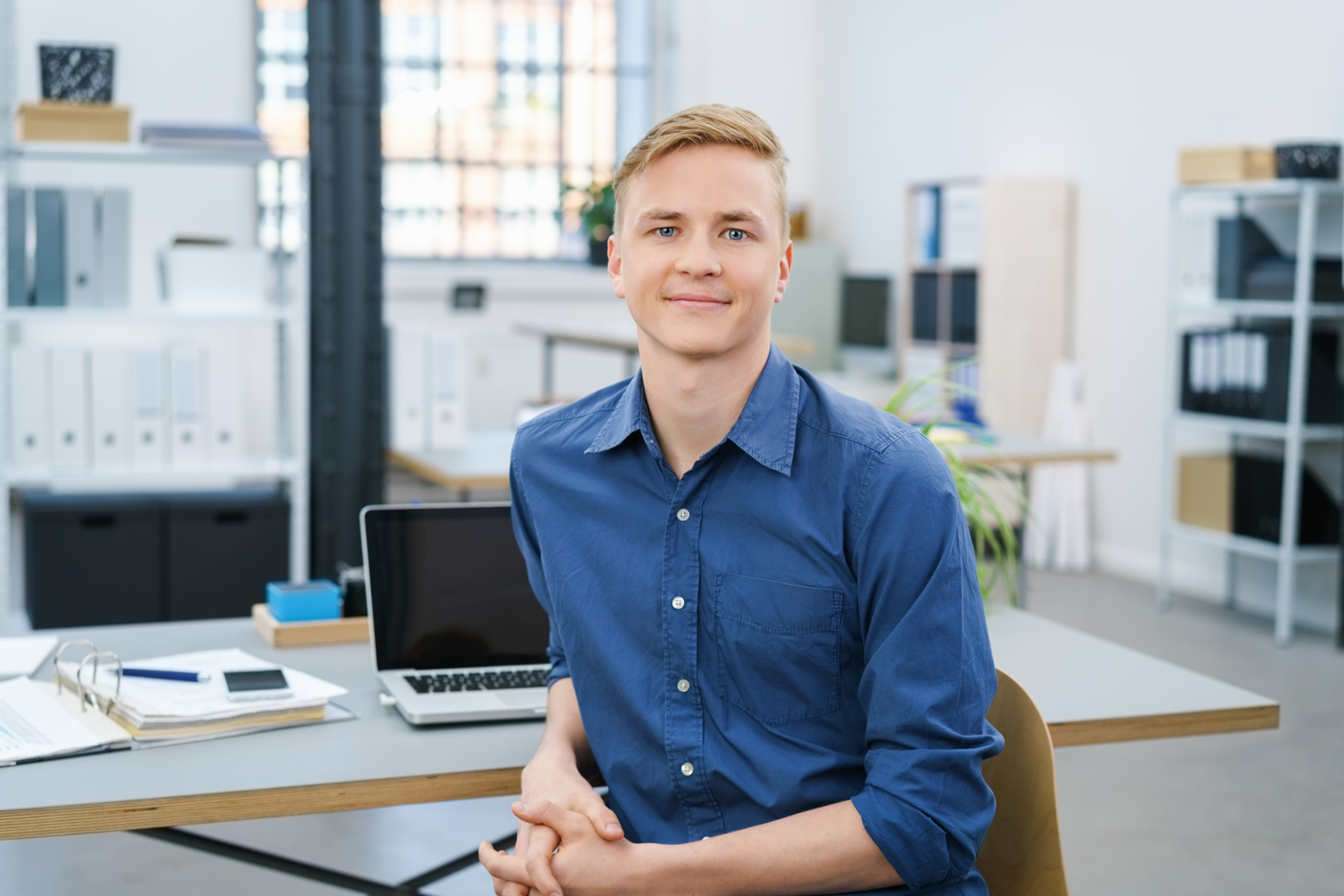 Ein Wirtschaftsfachmann sitzt an seinem Arbeitsplatz im Büro und beantwortet Kundenanfragen.